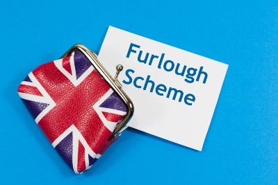Paper reading "furlough scheme" sticks out from a coin purse in the pattern of the UK flag - emergency furlough scheme