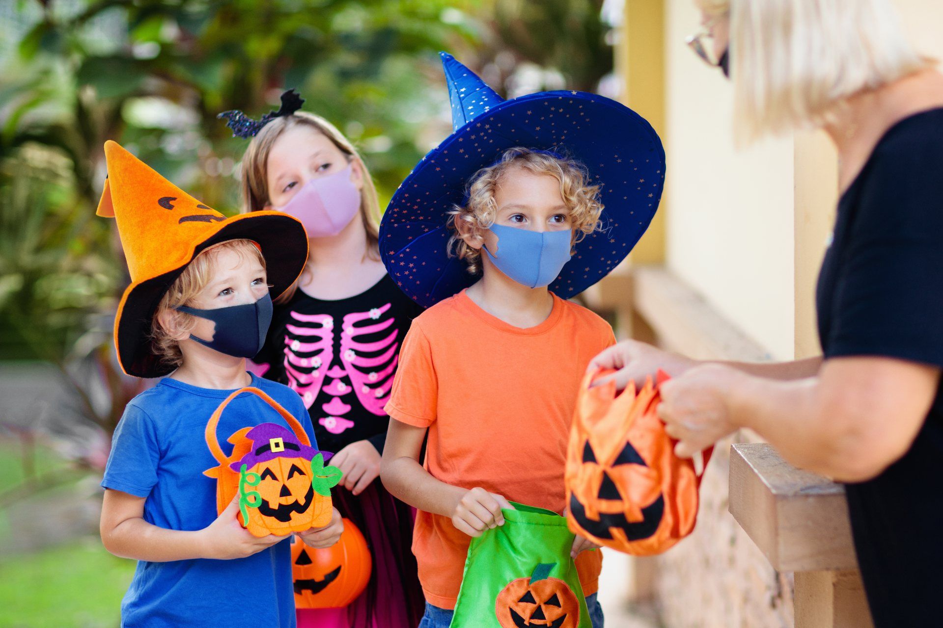 Children in face masks trick or treat on Halloween - halloween safety tips