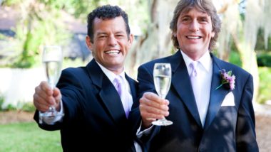 A male same-sex couple toasts with champagne at their wedding - civil partnerships