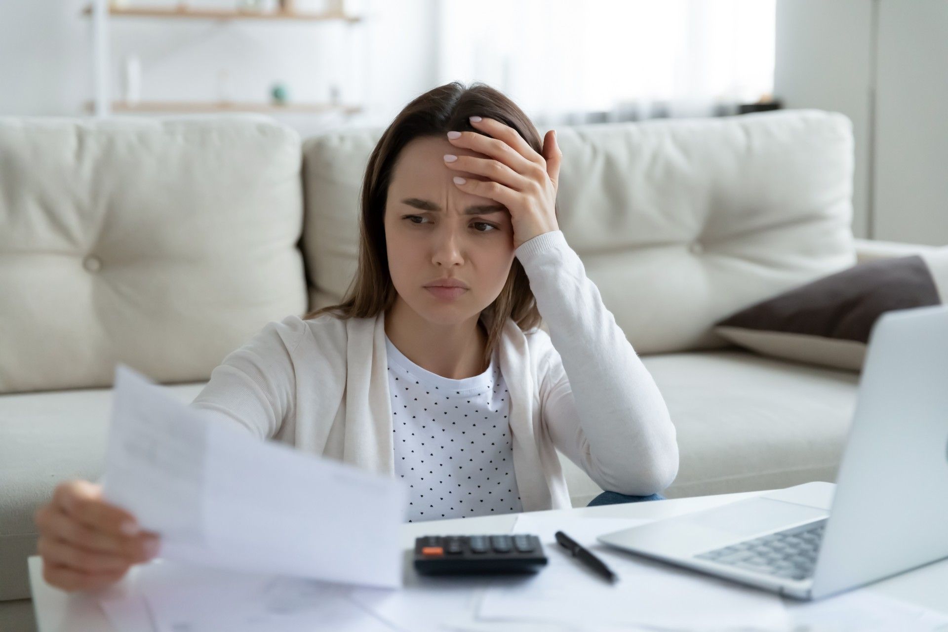 Woman with laptop and calculator is stressed about finances - payment holidays