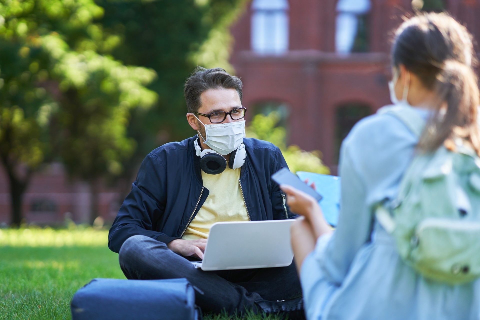 University students in masks sit on the grass while working and studying - rights at university