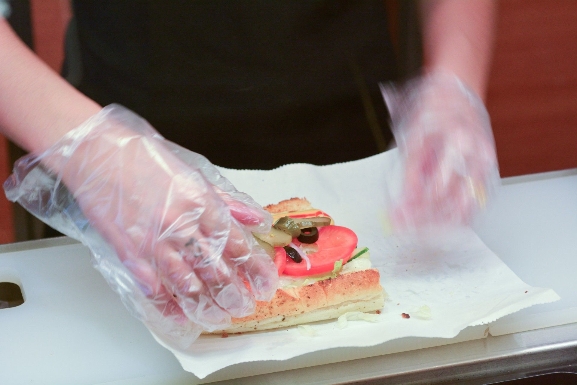 Sandwich shop employee makes a sub sandwich - Subway bread