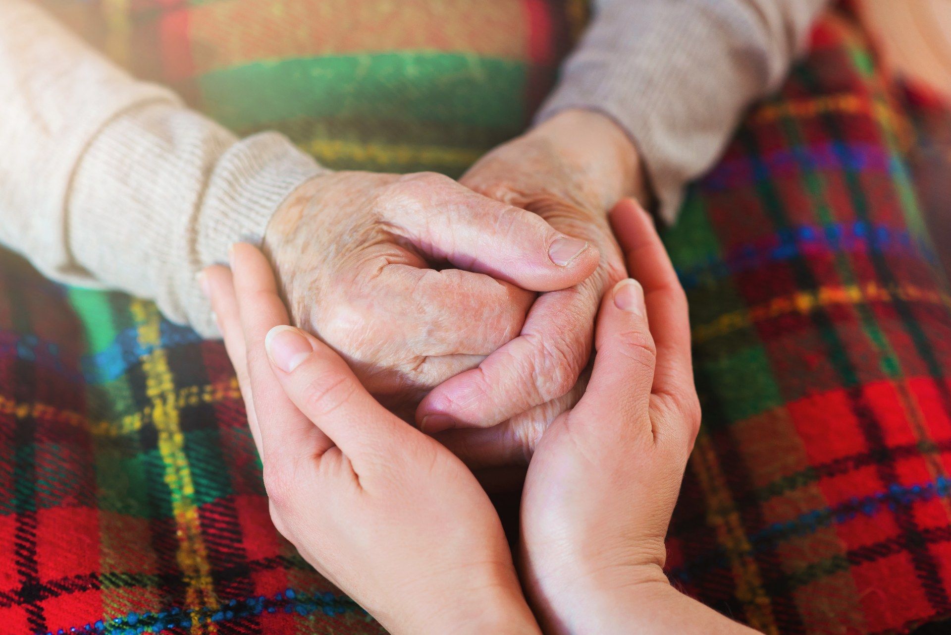 Closeup of a young person's hands holding the hands of an elderly person on their lap - glenabbey manor