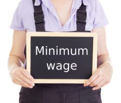 Employee holding minimum wage sign regarding companies short-changing workers