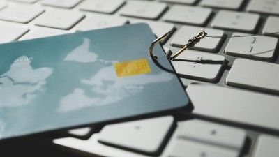 A credit card with a fishing hook lies on top of a keyboard - loqbox