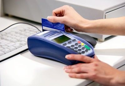 A person swipes a credit card through a POS system - Mastercard class action lawsuit