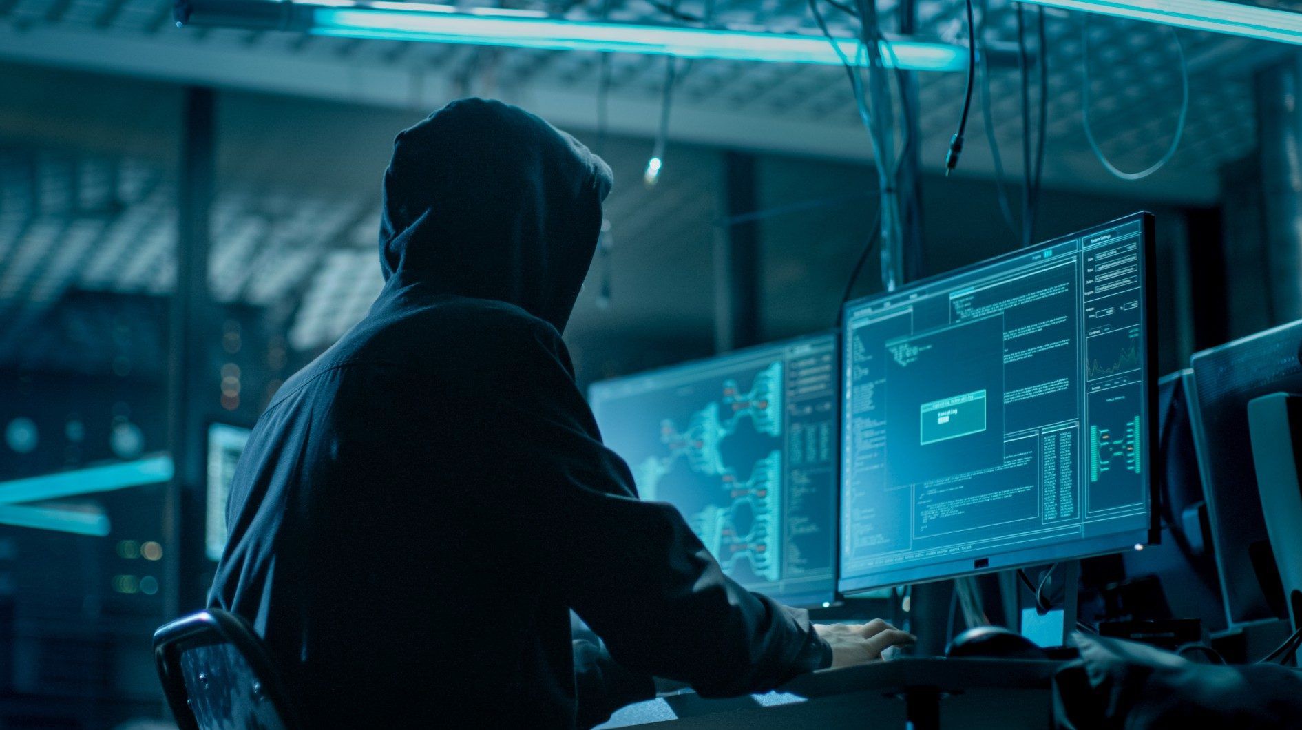 A hacker in a hoodie sits looking at a computer monitor - transform hospital group