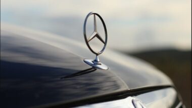 Close up of Mercedes emblem against a cloudy sky.