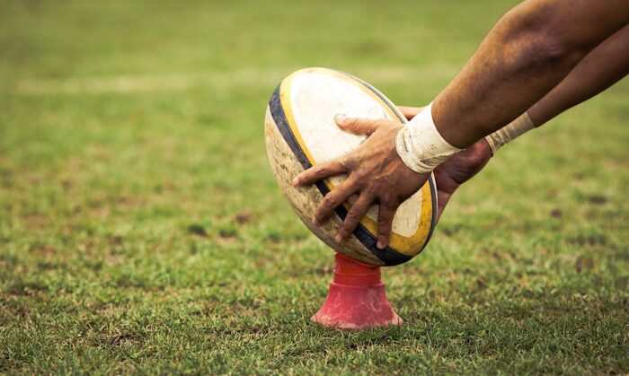 rugby player preparing to kick the oval ball during game.