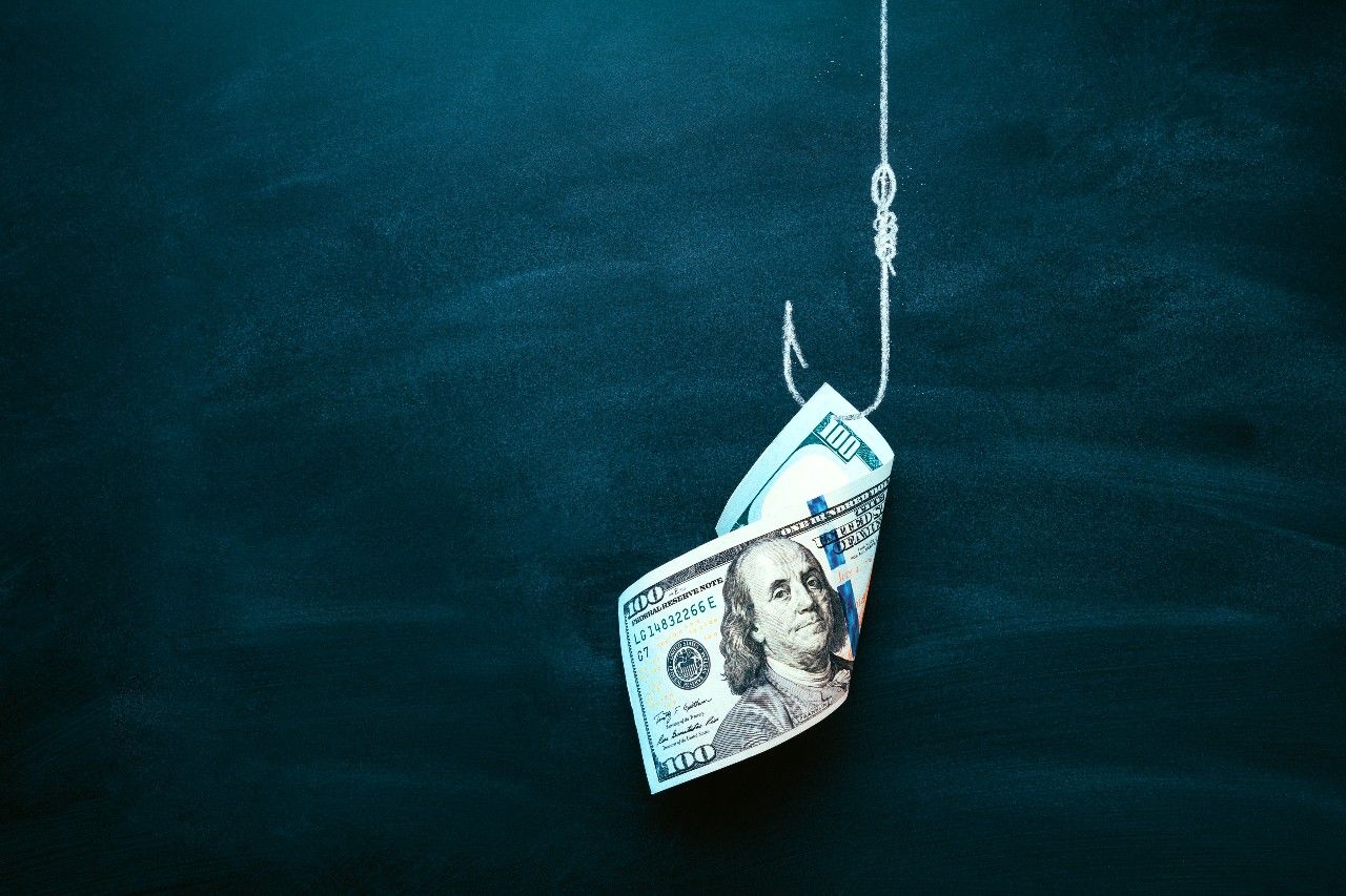 One hundred dollar bill on a fishing hook against a dark blue background. sweepstakes scam concept.