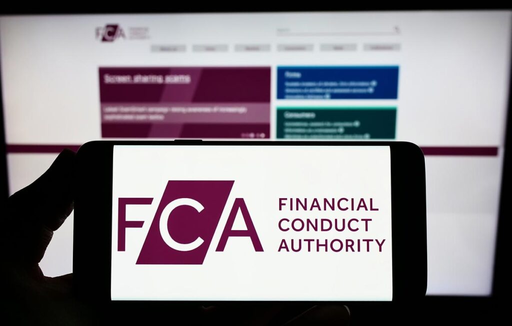 Person holding smartphone with logo of British Financial Conduct Authority (FCA) on screen in front of website.