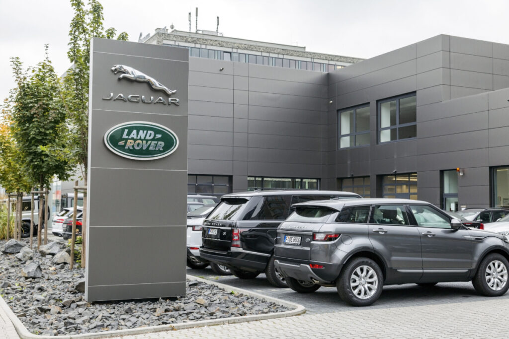 Jaguar Land Rover Sign outside dealership next to Land Rover SUVs
