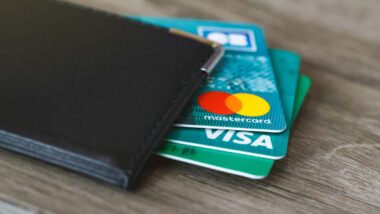 Mastercard and Visa cards peaking out of a wallet, representing the Mastercard and Visa fees cap.