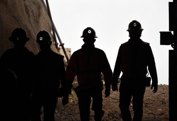 Silhouette of miners with headlamps entering a mine