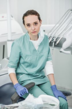 Female dentist sitting in dental office regarding the class action lawsuit filed against a insurance company for denying business loss claims amid COVID-19