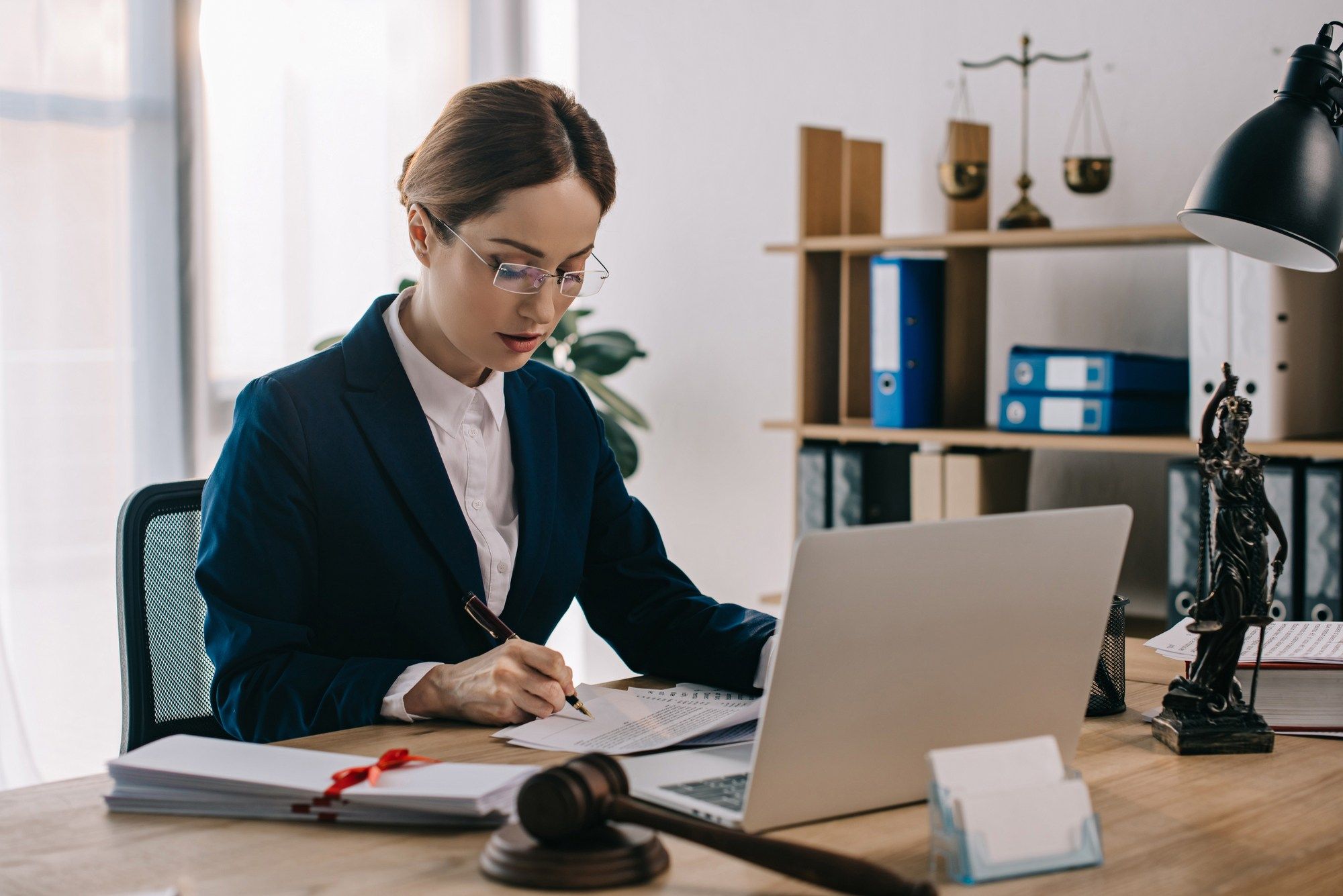 lawyer working at her desk regarding information on who covers the cost of a class action lawyer 