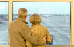 Older couple looking out the airport window regarding the class action filed against Air Canada over flight passes and retirement benefits 