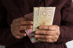 Person holding Canadian cash regarding information on how a class action rebate works.