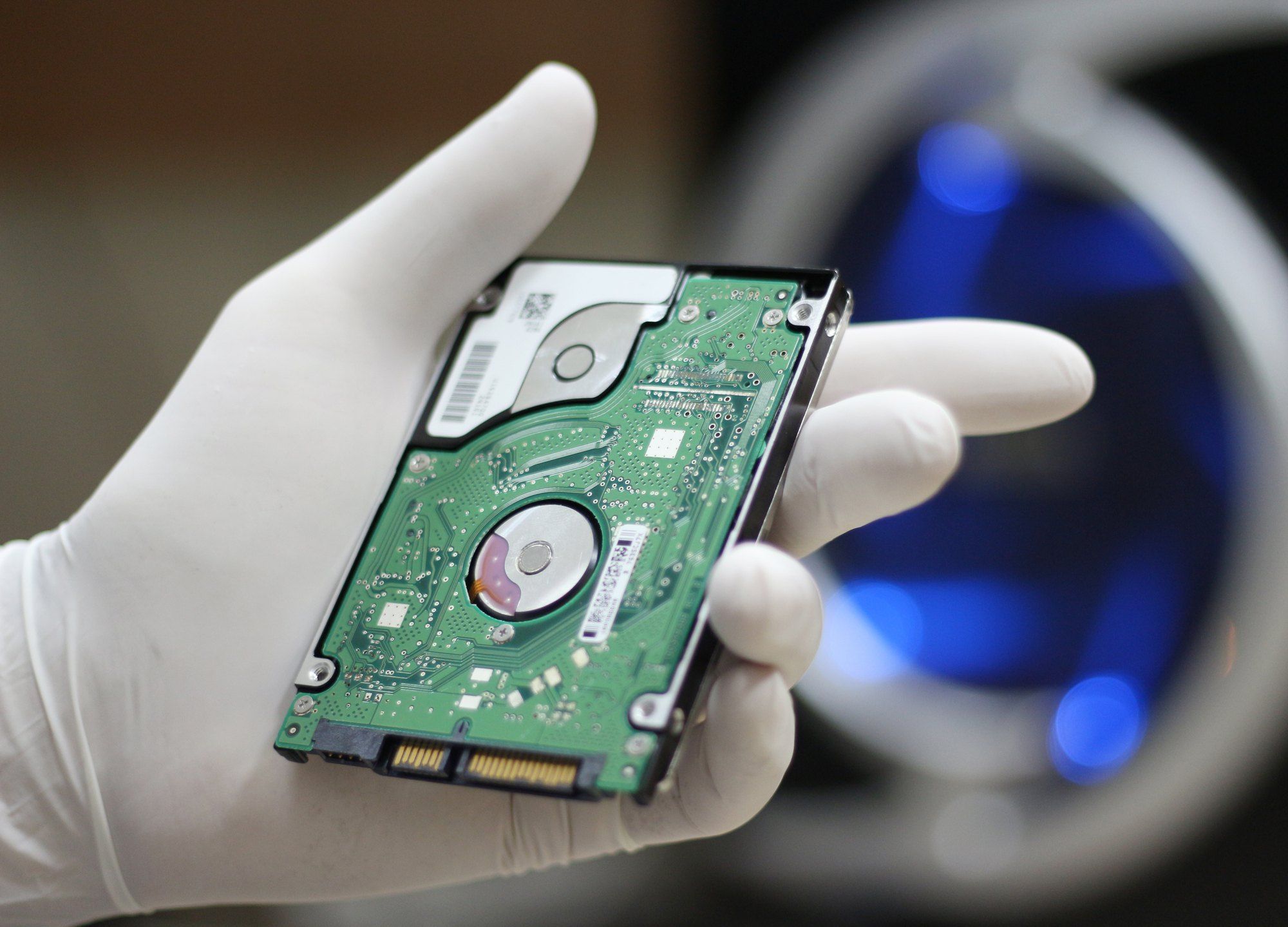 Gloved hand holding hard disc drive regarding the class action lawsuit filed against Western Digital 