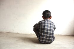 Aboriginal child sitting alone after being taken away from his family by CFS
