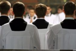 blurry view of young clerics in mass regarding the members of the Clerics of St. Viator being arrested for sexual abuse allegations 