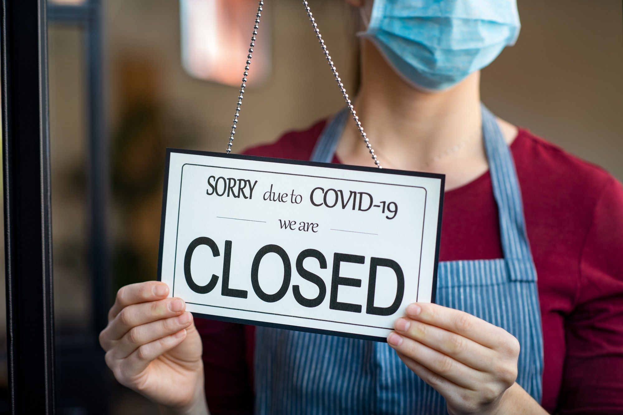 Person putting up closed due to COVID-19 sign regarding the Intact Insurance Company class action lawsuit filed 