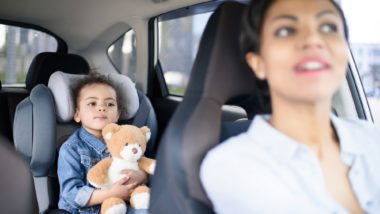 Woman looking back at baby in car seat regarding the Big Kid Booster seat class action lawsuit filed