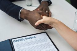 Shaking hands over disability insurance form regarding information about long term disability insurance in Canada