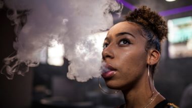 Woman vaping blowing smoke regarding the JUUL health risks class action lawsuit filed