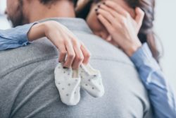 Woman crying holding baby shoes regarding the Adoption By Choice lawsuit filed