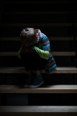 sad boy sitting on stairs regarding the orphanage abuse class action lawsuit filed