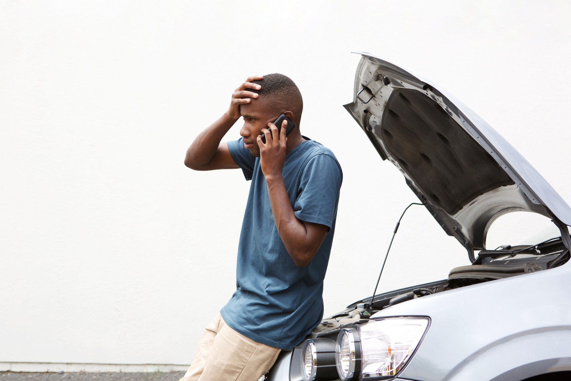 Man standing next to a stalled car regarding the Denso fuel pump defect