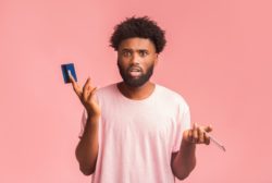 man shocked holding a card regarding the prepaid visa card class action lawsuit settlement reached 