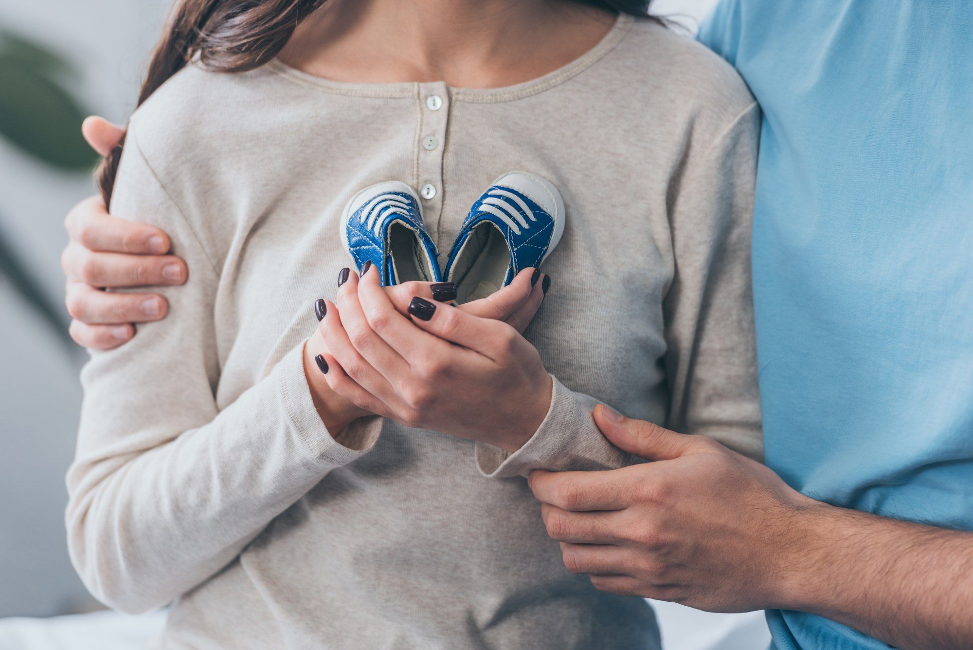 Woman holding baby shoes embraced by man regarding the Adoption By Choice lawsuit filed after the Calgary adoptions agency closed