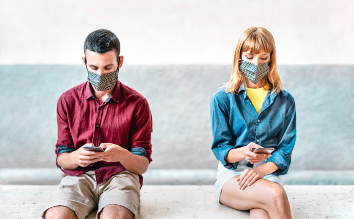 Two people on phones in masks checking COVID-19 tracking app