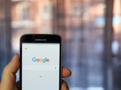 Person holding phone regarding Google advertising class action lawsuit 