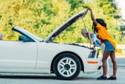 two women checking under hood of car for defects