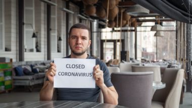 Business owner holding closed sign regarding information on business interruption insurance coverage