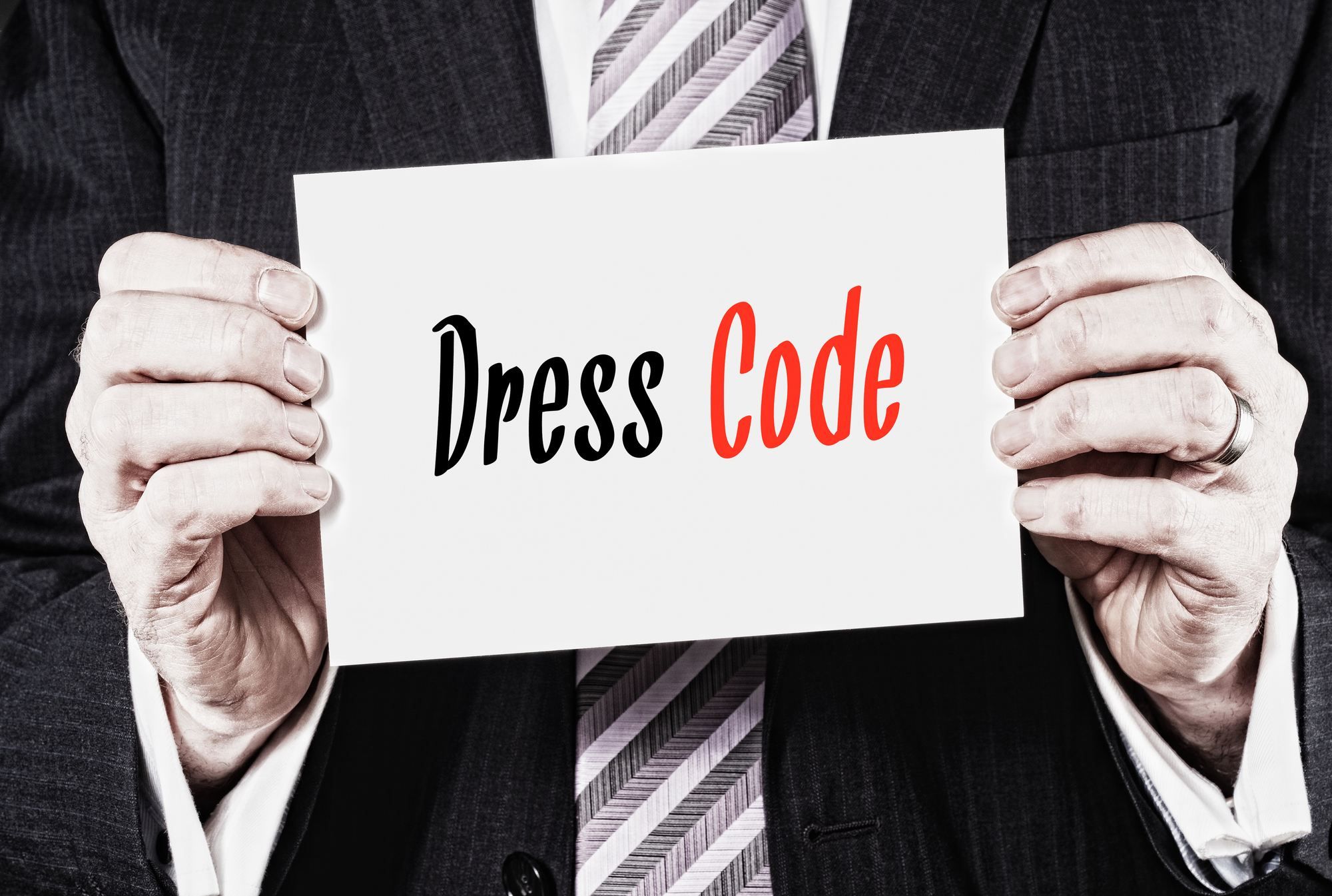 Man holding dress code sign regarding the Edmonton woman fired over the clothes she wore