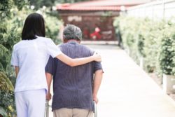nurse walking elderly man in long-term care home in ontario