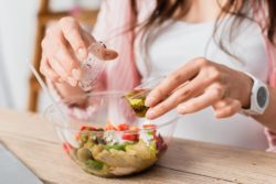 woman pouring salad dressing on allergy infested salad