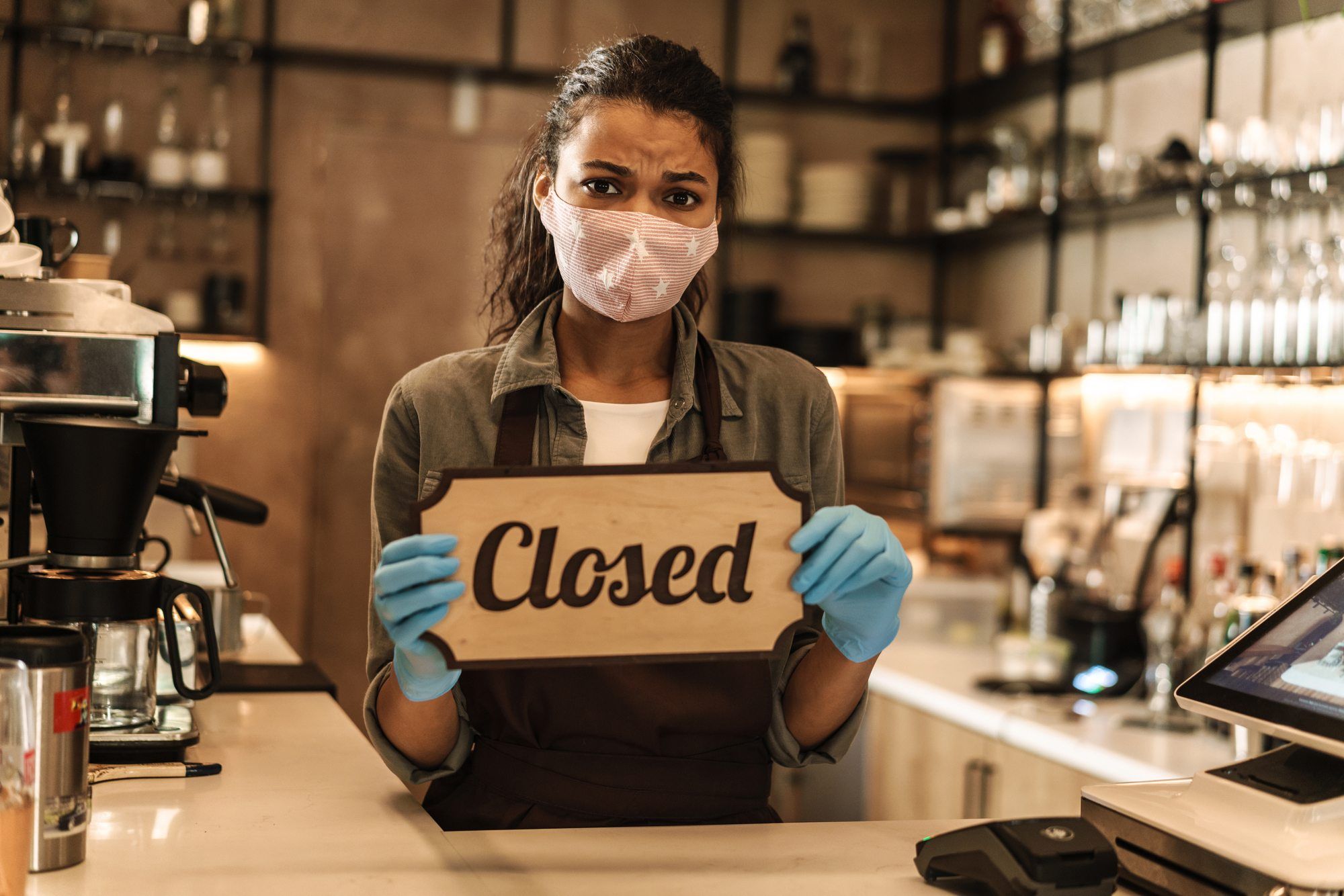 Business owner holding a closed sign amid cOVID regarding information on What Should You Know When Filing a Business Interruption Claim Letter?