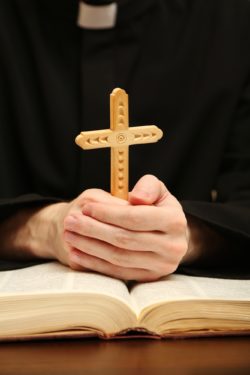 Priest holding wooden cross amid sexual abuse claims