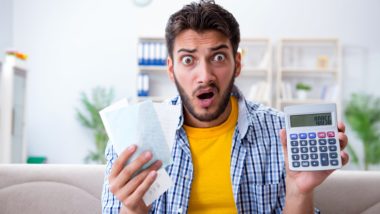 A shocked man holds receipts and a calculator - overdraft fees