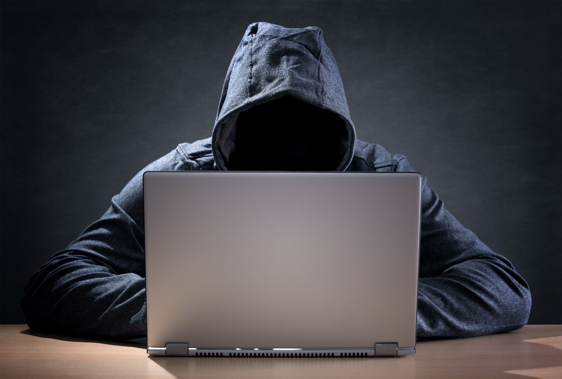A hacker in a hoodie uses a laptop - dell canada