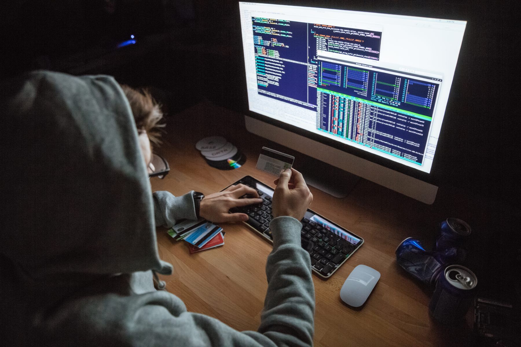 A hacker in a grey hoodie uses a credit card online - dell