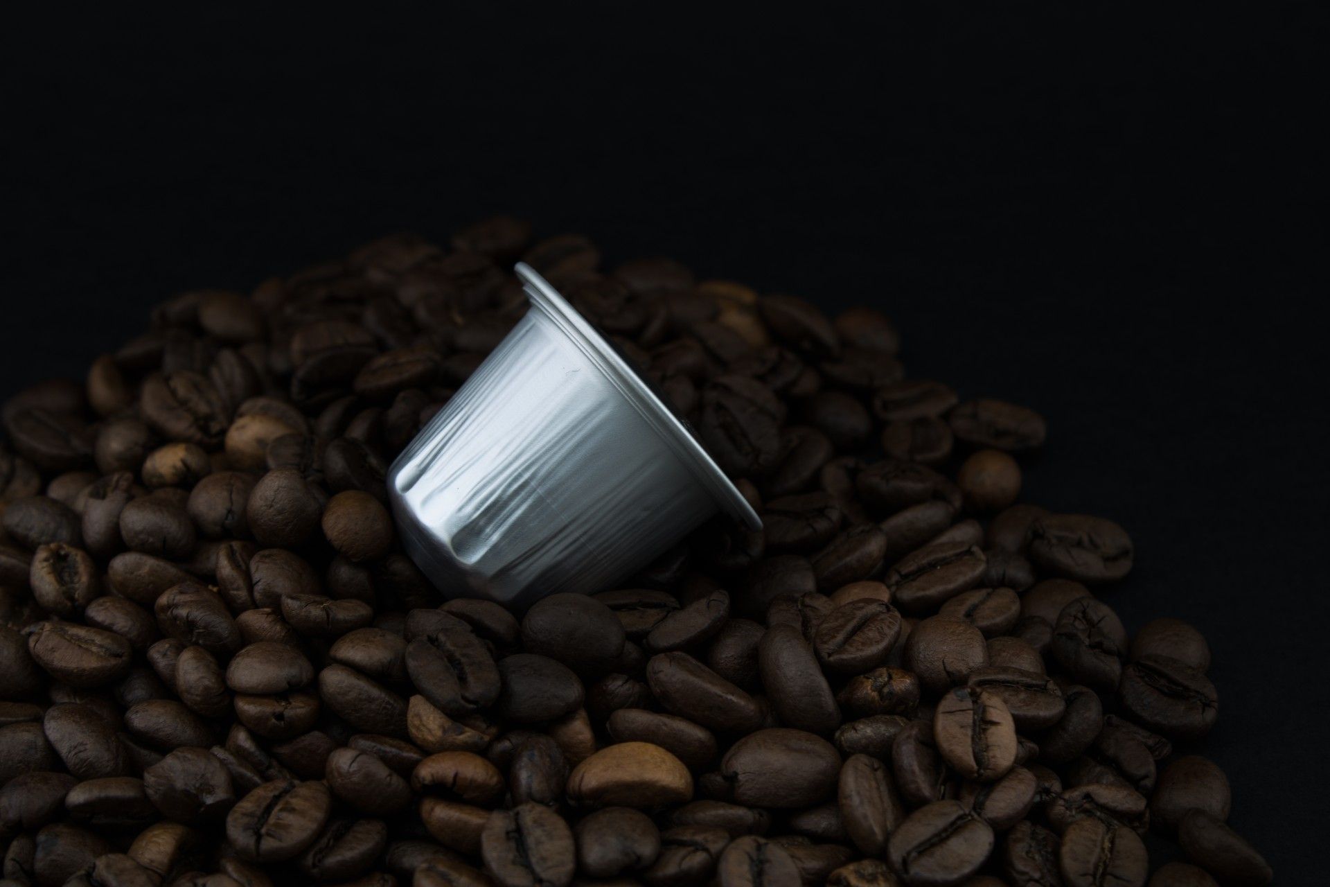 Silver coffee pod on pile of coffee beans - are k-cups recyclable
