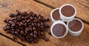 Coffee pods sit next to a stack of coffee beans - keurig k-cups