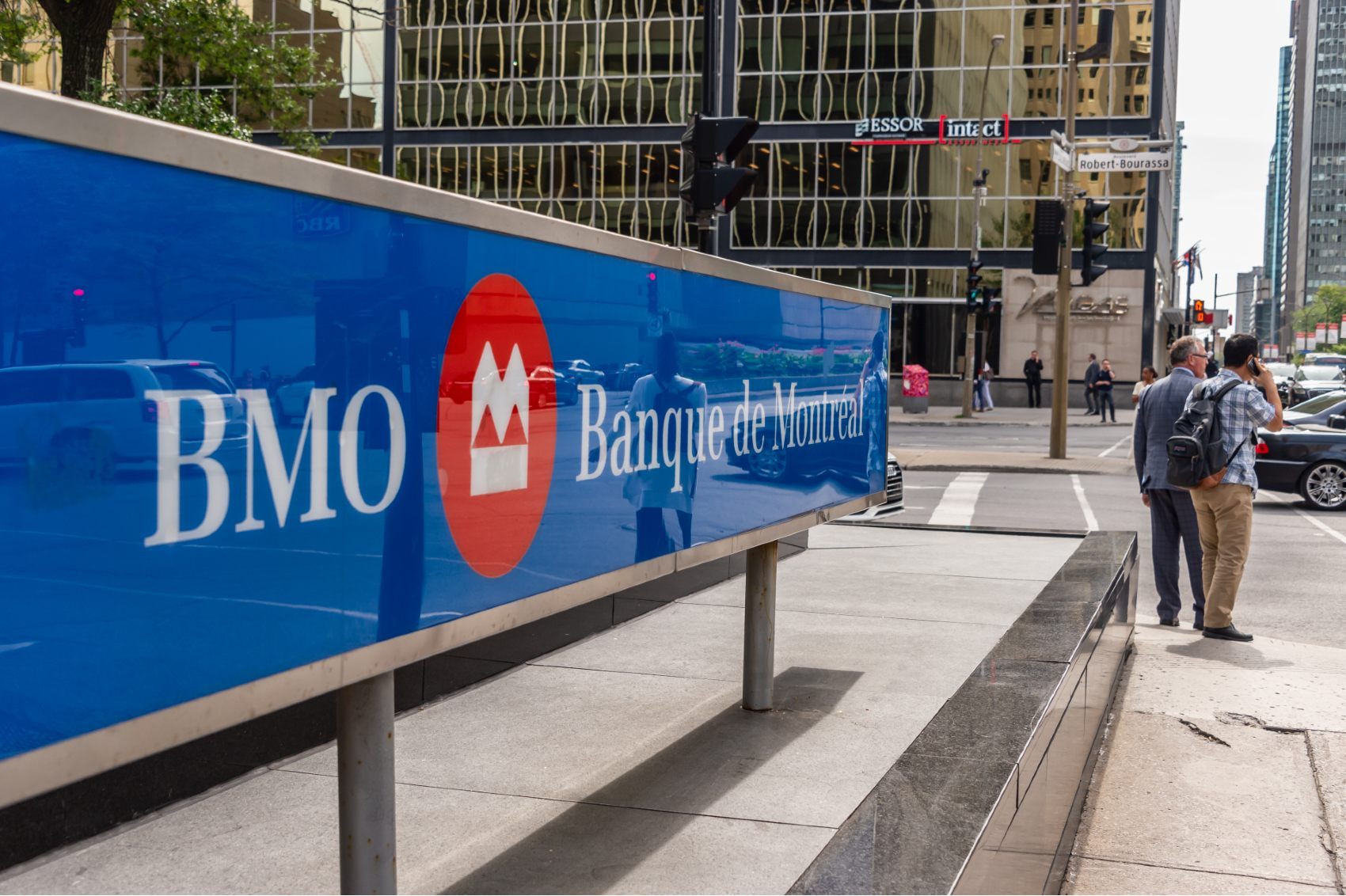 People stand on a corner near a BMO Bank of Montreal sign - cibc
