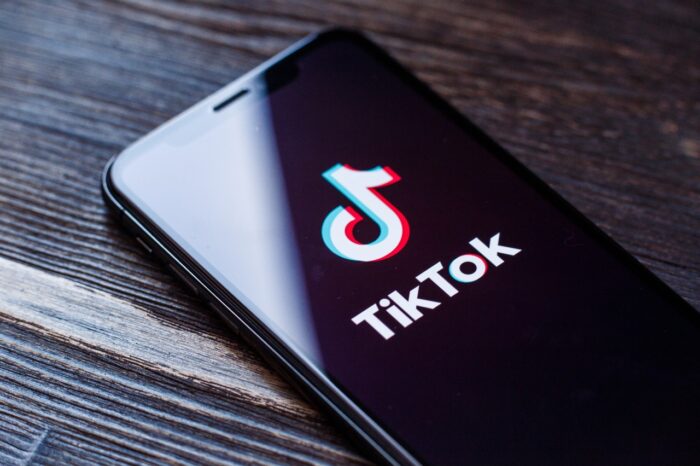 TikTok application icon on Apple iPhone X screen close-up.